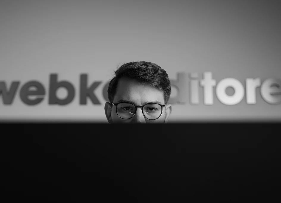 Mann mit Brille schaut konzentriert auf einen Computerbildschirm in einem modernen Büro.